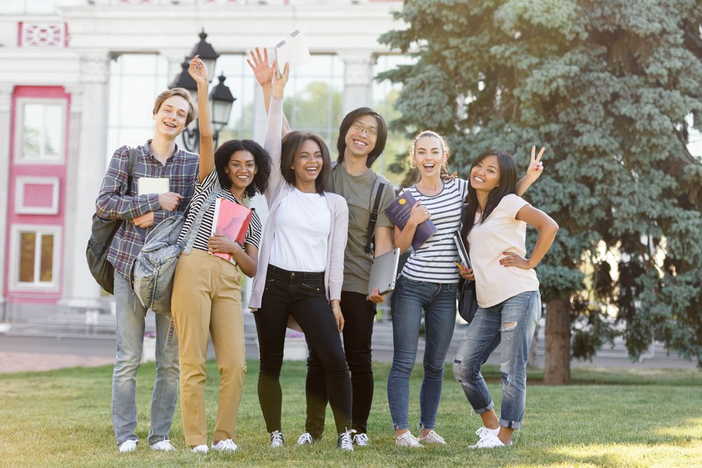 9 International Education Advantages For Students 2 cheerful students standing waving outdoors min